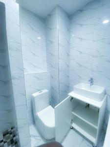 a white bathroom with a toilet and a sink at Cozy Up on 5th in Harare +5 photos