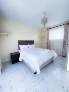 a bedroom with a large white bed and a chandelier at Cozy Up on 5th in Harare