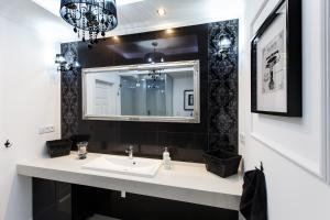 La salle de bains est pourvue d'un lavabo et d'un miroir. dans l'établissement Apartamenty Sienkiewicza - bezpłatny parking, centrum, park, fv, à Kielce