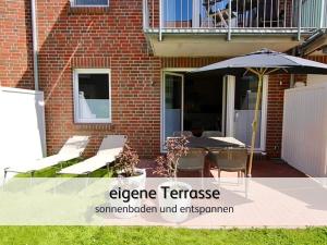 诺登Ideal für Familien & Fellnasen, strandnah的带遮阳伞、桌椅的露台