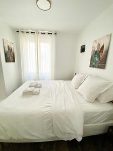 a white bed in a white bedroom with a window at Maison le Bac Apartments in Paris