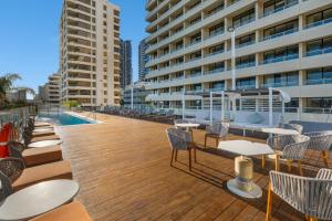 a deck with chairs and tables and a swimming pool at Crowne Plaza Perth by IHG in Perth