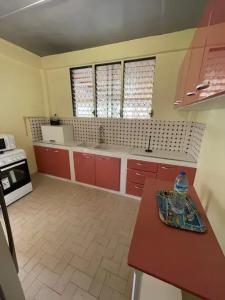 a kitchen with red cabinets and a table in it at Appartement chaleureux à Fort-de-France de 92 m² in Quartier Châteauboeuf