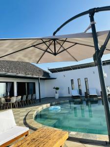 a pool with an umbrella and chairs and a table at Villa ANAYA in Nosy Be