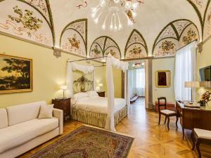 a bedroom with a bed and a couch and a chandelier at Relais degli Angeli Residenza d'Epoca in Siena