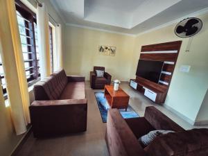 a living room with couches and a flat screen tv at Tranquil Nest Villa - Wayanad in Kalpetta