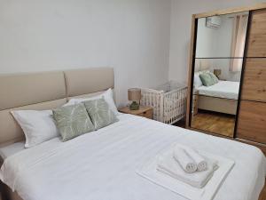 a bedroom with a white bed with two towels on it at Apartman IGOR Trebinje in Trebinje