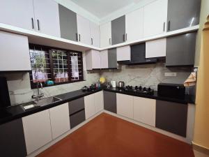 a kitchen with white cabinets and black counter tops at Tranquil Nest Villa - Wayanad in Kalpetta
