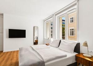 a white bedroom with a large bed and windows at Limehome Karlsruhe Kaiserstraße in Karlsruhe