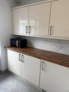a kitchen with white cabinets and a microwave on a counter at Beautiful Apartment in Burstwick