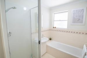 a white bathroom with a tub and a sink at Coastal Garden Villa in Albany +30 photos