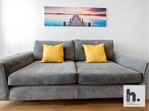 eine graue Couch mit zwei gelben Kissen in einem Wohnzimmer in der Unterkunft Free Parking - Balcony - Siemens - Perfect for Business & Weekends x6 Units in Hull