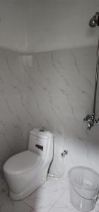 a white bathroom with a toilet and a bowl at Mezbaan Guest House in Nathia Gali +42 photos