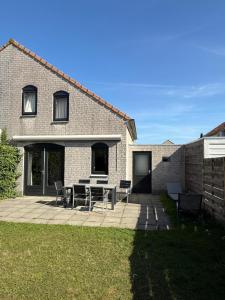 a patio with a table and chairs in front of a house at Vakantiehuis Strand ,water,met infraroodsauna in Breskens +19 photos