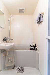 a white bathroom with a sink and a bath tub at リトリートコート西新 in Fukuoka