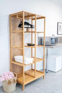 estantería de madera con toallas y microondas en Pink Muse, 3 Mins To Ettalong Beach, en Ettalong Beach