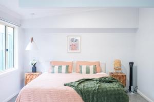 1 dormitorio blanco con 1 cama con manta verde en Pink Muse, 3 Mins To Ettalong Beach, en Ettalong Beach