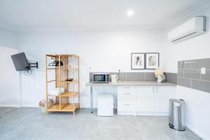 cocina blanca con encimera y microondas en Pink Muse, 3 Mins To Ettalong Beach, en Ettalong Beach 4 fotos más