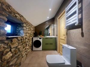 a bathroom with a stone wall and a washer and dryer at Villa Stone House in Kutaisi Heliport