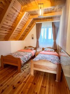 two beds in a room with wooden floors at Villas Hidden Paradise in Žabljak