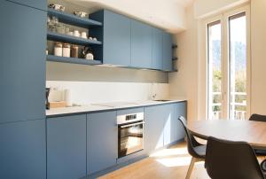 a kitchen with blue cabinets and a table and chairs at Wake of the lake - bright waterfront apartment in Lecco