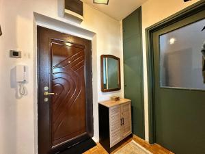 a bathroom with a wooden door and a mirror at Prishtina Center Apartment in Pristina