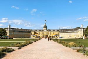 a large yellow building with people walking down a pathway at Limehome Karlsruhe Kaiserstraße in Karlsruhe