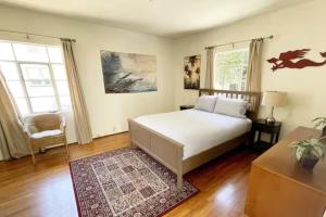 a bedroom with a bed and a chair and windows at The Marlowe Seaside Villa in Santa Barbara