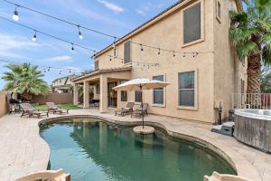 une piscine avec un parasol devant une maison dans l'établissement Chill & Thrill | Pool, Hot Tub • Family Game Villa, à Casa Grande