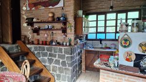 a kitchen with a brick wall and a refrigerator at Casa rustica Ilhabela a 200 m da praia do Julião in Ilhabela +19 photos
