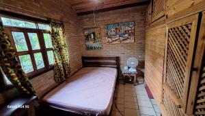 a small bedroom with a bed in a brick wall at Casa rustica Ilhabela a 200 m da praia do Julião in Ilhabela