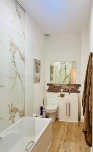 a white bathroom with a tub and a toilet at Luxury flat next to Blyth Port in Blythe