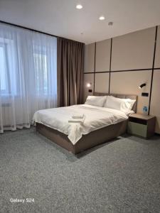 a bedroom with a large bed and a window at Set Sail Hotel in Uralsk