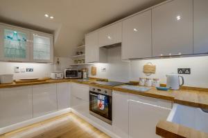 a kitchen with white cabinets and a stove top oven at Finn Cottage in Bamburgh +9 photos