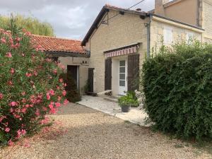 a brick house with a white door and two bushes at Gite VILLENEUVE LA COMTESSE in Villeneuve-la-Comtesse