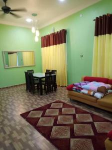 a living room with a bed and a table and chairs at Idaman Homestay 1 in Kampong Gong Kempas +3 photos