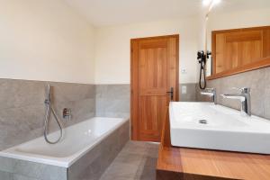 La salle de bains est pourvue d'une grande baignoire blanche et d'un lavabo. dans l'établissement Oberfahrerhof Jenesien, à Meltina 34 autres photos