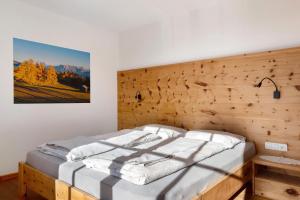 un lit dans une chambre avec un mur en bois dans l'établissement Oberfahrerhof Jenesien, à Meltina