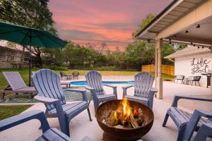 eine Feuerstelle auf einer Terrasse mit Stühlen und einem Pool in der Unterkunft Das Bach Haus - Game Room Make-Up Room & Hot Tub in Fredericksburg