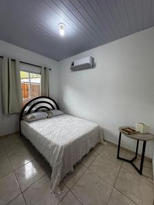 Un dormitorio con una cama y una mesa y una ventana. en Jack Beach House, en Palhoça