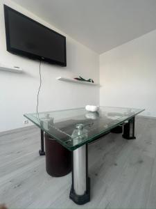 a glass table with a television on a wall at Apartament Fantasy in Craiova