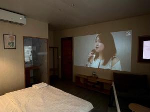 a bedroom with a large screen with a woman holding a microphone at Flourish Homestay in Mộc Châu