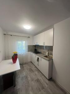 a kitchen with white cabinets and a sink and a table at Apartament Fantasy in Craiova
