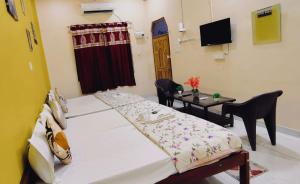 a room with two beds and a table and a television at ATULYAM STAYs PREMIUM in Ayodhya