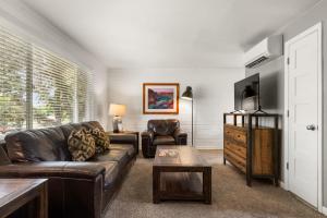 a living room with a leather couch and a tv at Downtown Cozy Home Base - Purple Sage 3 in Moab