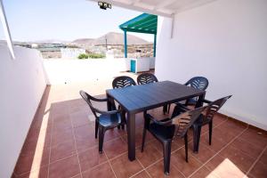 a black table and chairs on a balcony at Casa Kalendra Rofe Tu refugio cerca del mar in Guatiza