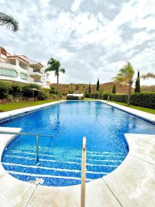 ein großer blauer Swimmingpool vor einem Haus in der Unterkunft Delicate child friendly ground floor apartment in Mijas Costa