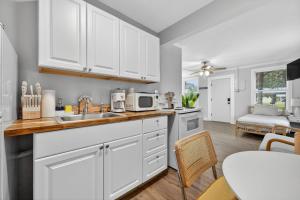 a kitchen with white cabinets and a sink and a table at Unit 19 Tiny Haven Unwind in Pensacola in Pensacola