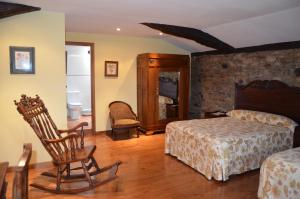 a bedroom with two beds and a chair in it at Casa de Martiño in Friol