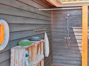 a shower in a sauna with a wooden wall at Holiday Home Mariam - 100m from the sea by Interhome in Åkirkeby